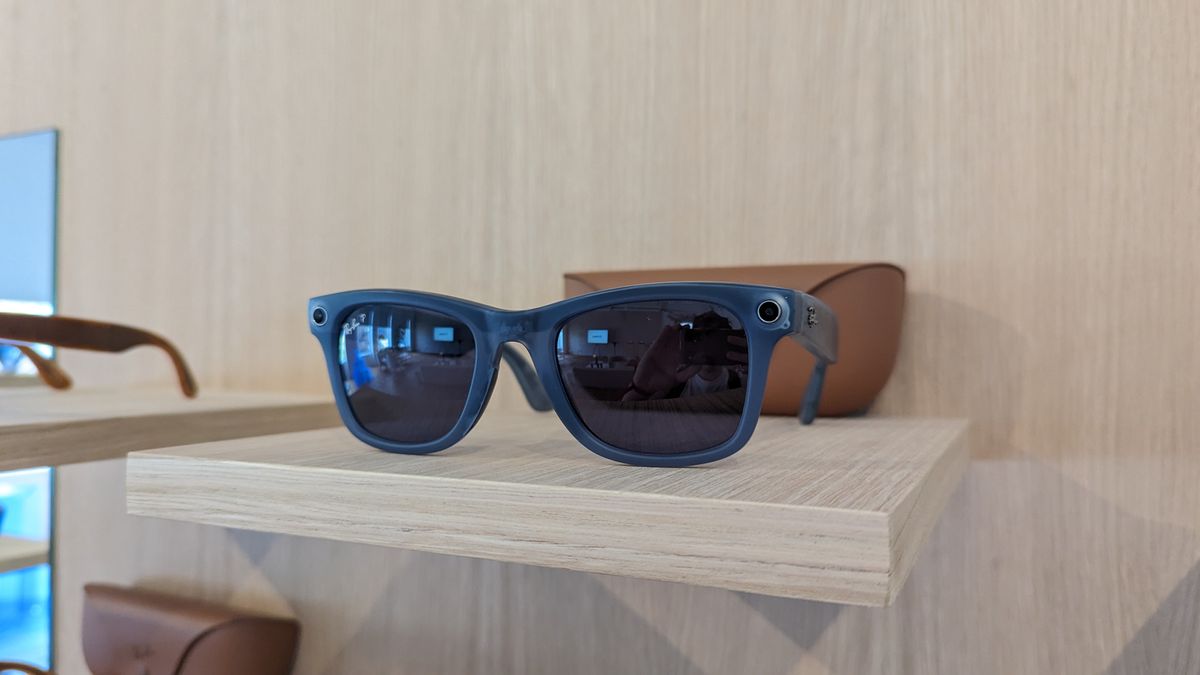 A blue pair of the Ray-Ban Meta Smart Glasses Collection on a wooden table in front of their charging case